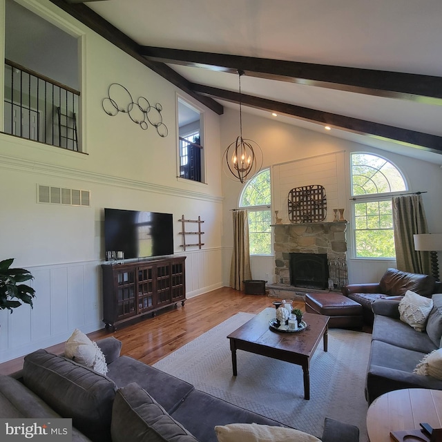 living room with an inviting chandelier, visible vents, a wealth of natural light, and wood finished floors