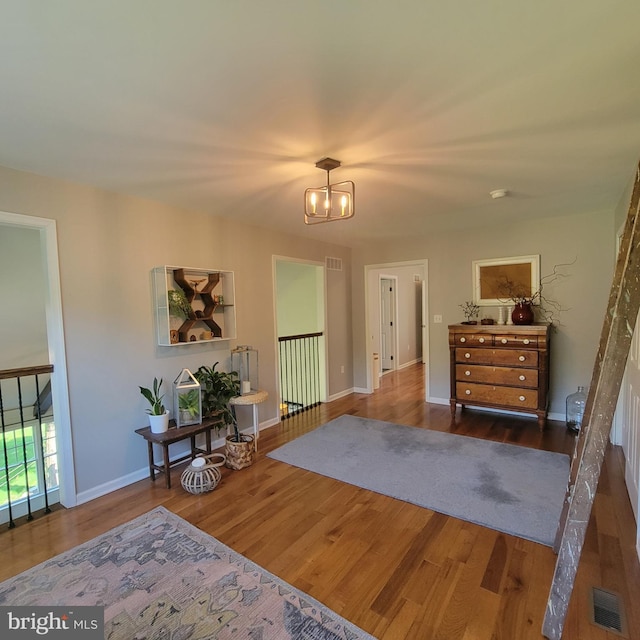 bedroom featuring visible vents, wood finished floors, a notable chandelier, and baseboards