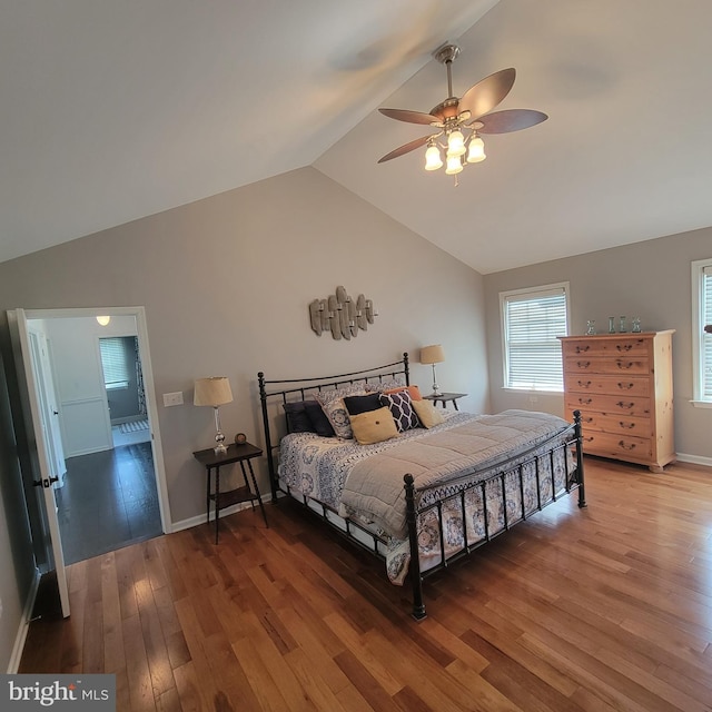 bedroom with ceiling fan, freestanding refrigerator, baseboards, vaulted ceiling, and wood finished floors