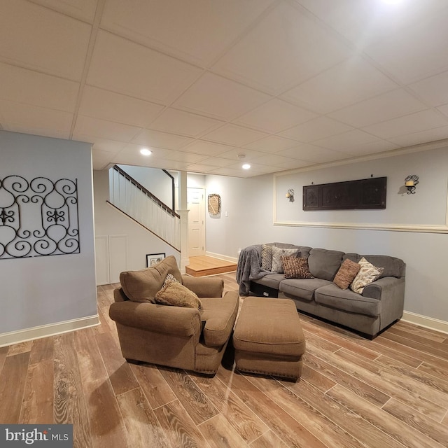 living area featuring recessed lighting, a paneled ceiling, stairs, baseboards, and wood finished floors