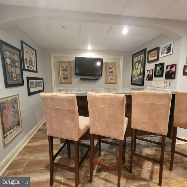 bar with wood finished floors, recessed lighting, wet bar, and baseboards