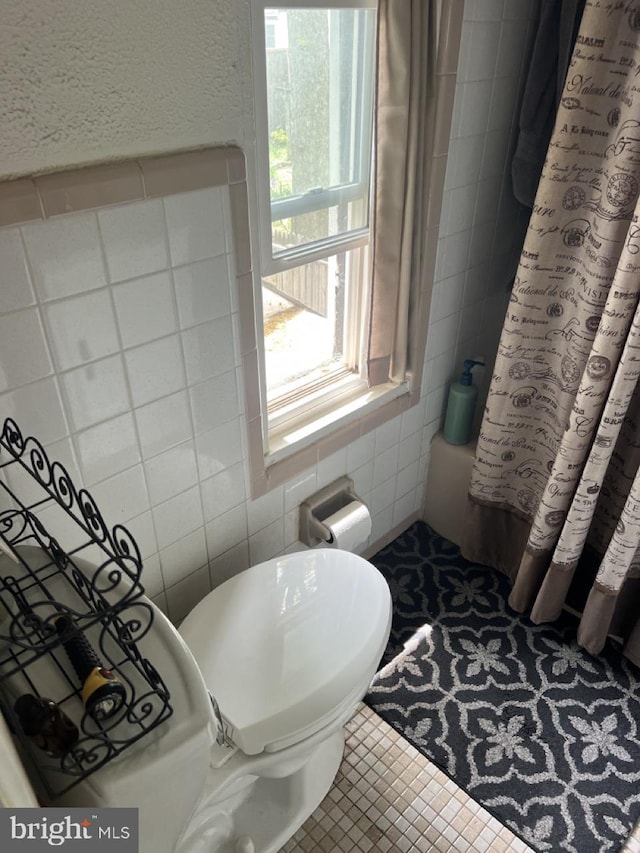 full bath featuring tile walls, toilet, and curtained shower