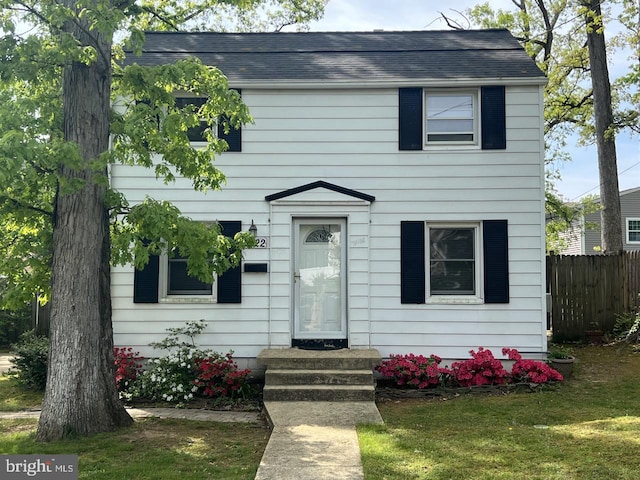 colonial home with fence and a front lawn