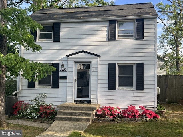 view of front facade featuring central air condition unit, fence, and a shingled roof