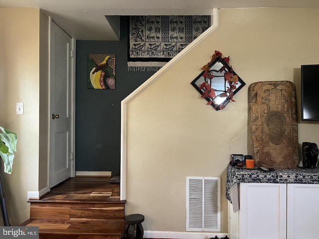 stairs with baseboards, visible vents, and wood finished floors