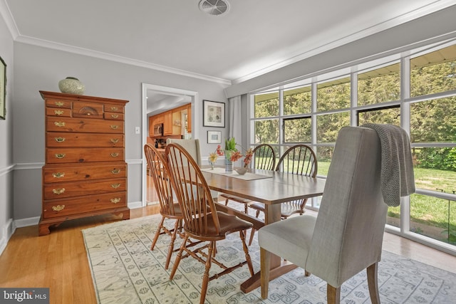 dining area with baseboards, ornamental molding, light wood finished floors, and visible vents