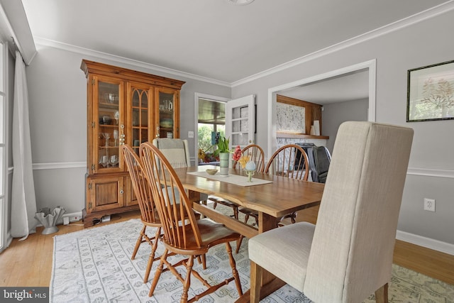 dining area featuring crown molding, baseboards, and light wood-type flooring