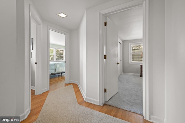 corridor featuring light wood-style floors and baseboards