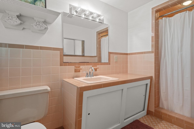 bathroom featuring a shower with curtain, tile walls, vanity, a wainscoted wall, and toilet