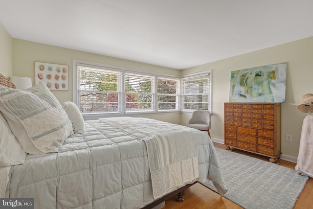 bedroom with baseboards, multiple windows, and wood finished floors
