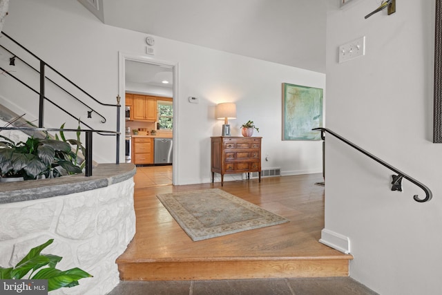 interior space with baseboards, visible vents, light wood-style flooring, and stairway