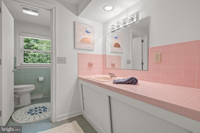 bathroom with toilet, tile patterned floors, tile walls, and vanity