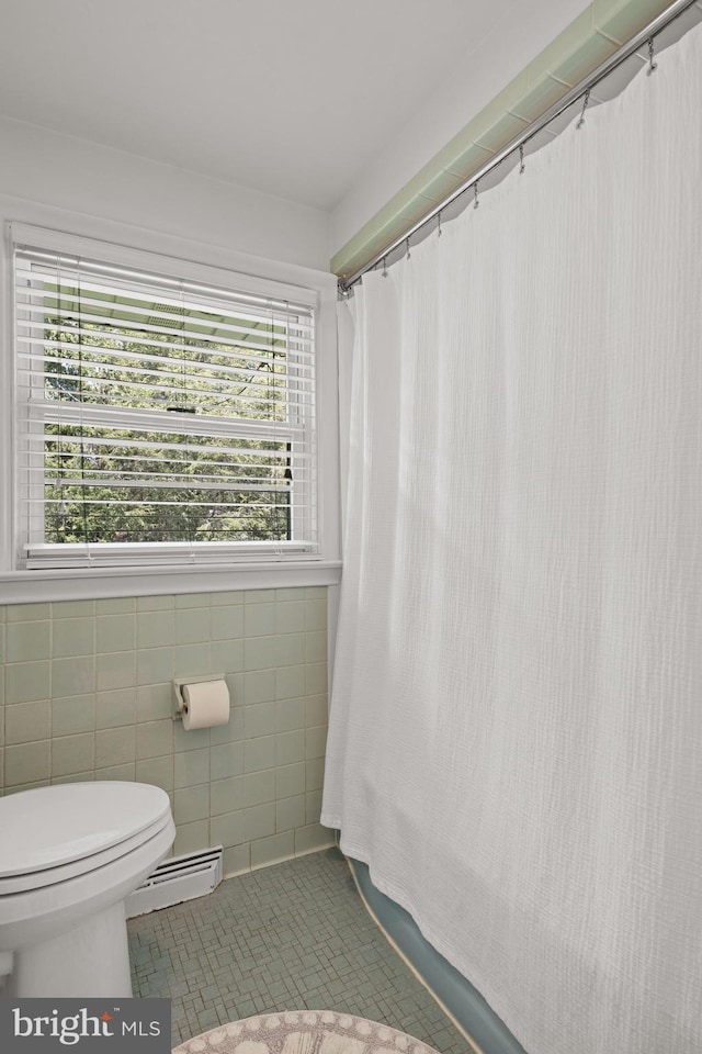 full bath featuring a shower with curtain, baseboard heating, toilet, and tile walls