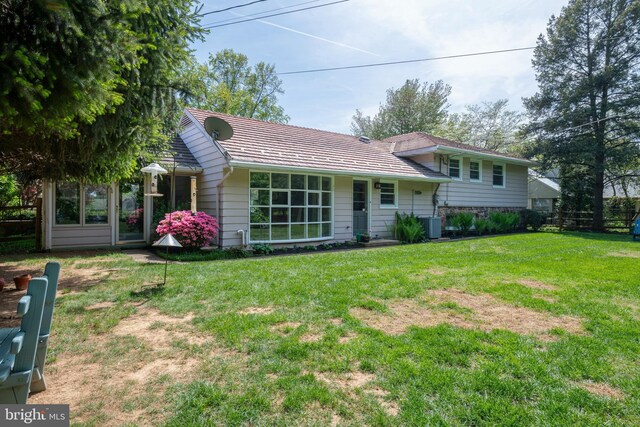 view of front facade featuring fence, central AC unit, and a front lawn