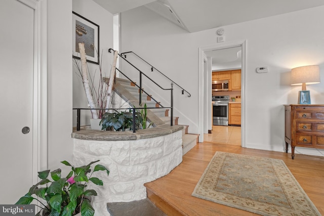entrance foyer with baseboards, stairway, and light wood-style floors