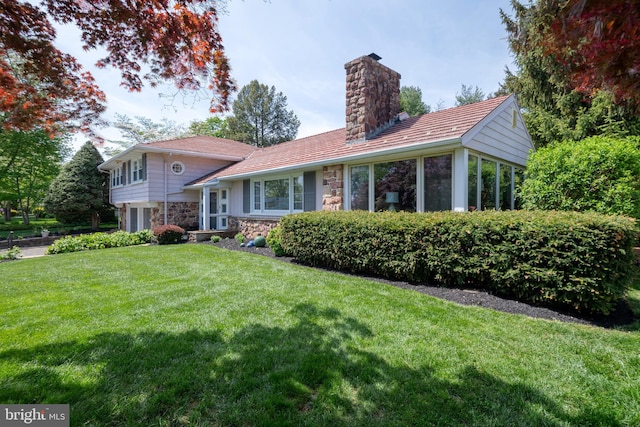 view of front of house featuring a front lawn, stone siding, and a chimney