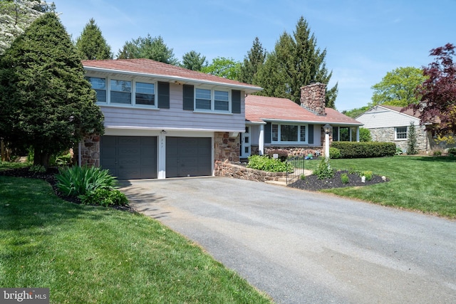 split level home featuring a chimney, an attached garage, driveway, and stone siding