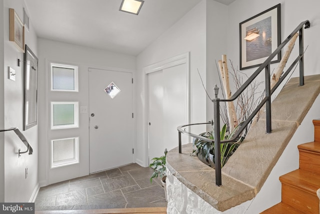 foyer featuring visible vents, stone tile floors, baseboards, and stairs