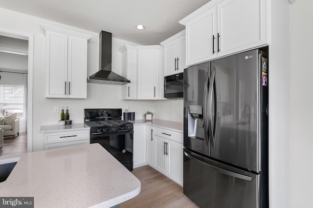 194 Cool Springs Road, North East, MD 21901 - kitchen with white cabinets, black appliances, light stone countertops, light wood finished floors, and wall chimney exhaust hood