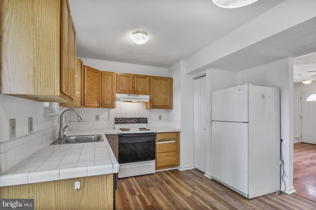 kitchen with dark wood-style flooring, a sink, white appliances, tile countertops, and under cabinet range hood