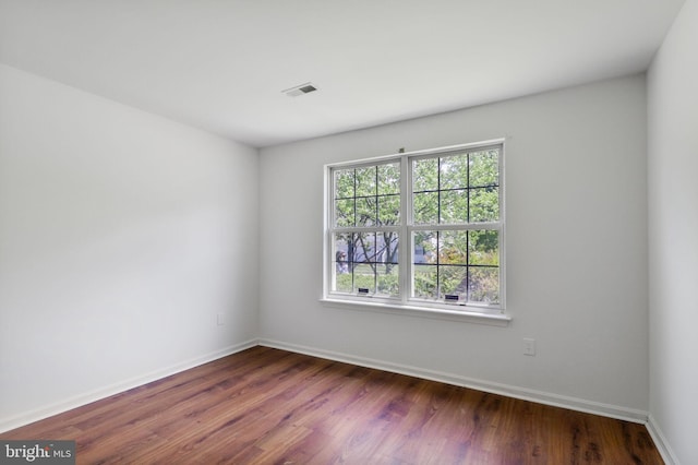spare room featuring visible vents, dark wood finished floors, and baseboards