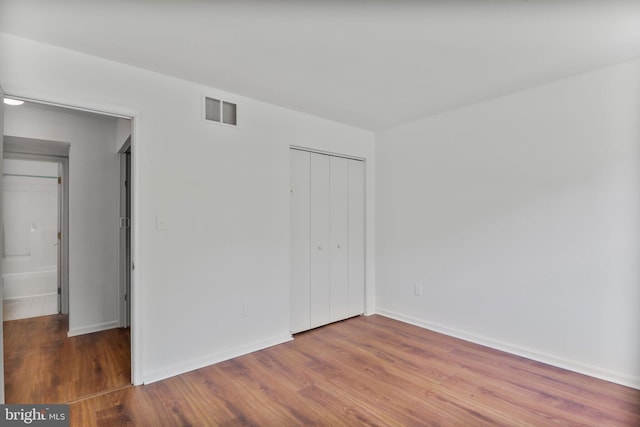 unfurnished bedroom featuring visible vents, baseboards, wood finished floors, and a closet