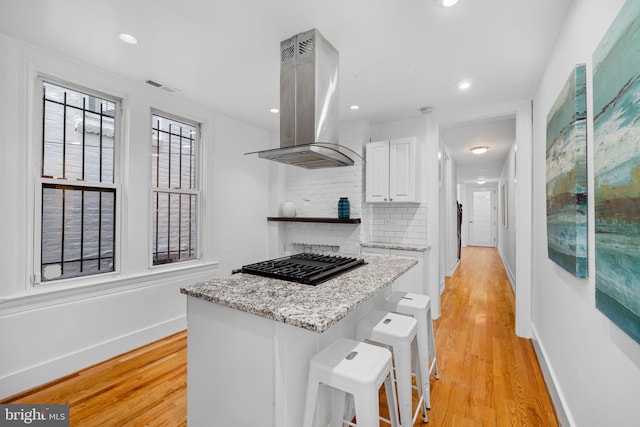 1524 5th St NW, Washington, DC 20001 - kitchen with visible vents, decorative backsplash, island range hood, black stovetop, and white cabinetry