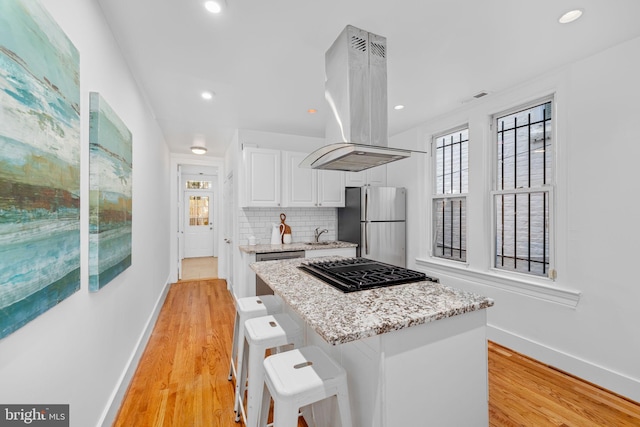 1524 5th St NW, Washington, DC 20001 - kitchen with light stone countertops, appliances with stainless steel finishes, white cabinetry, baseboards, and island exhaust hood