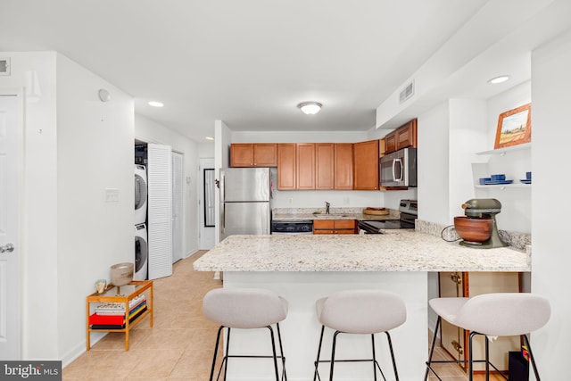 1524 5th St NW, Washington, DC 20001 - kitchen with brown cabinetry, a peninsula, stacked washing maching and dryer, a kitchen breakfast bar, and stainless steel appliances