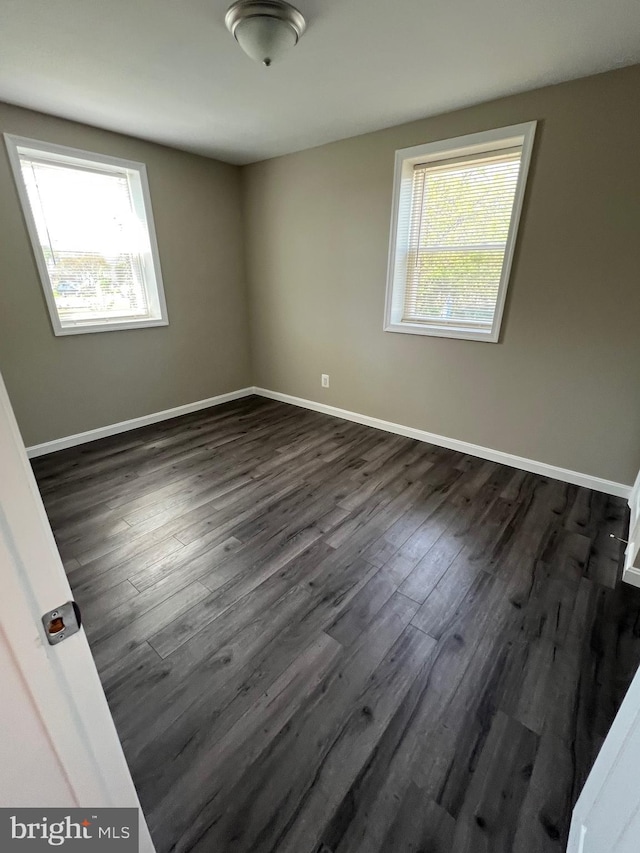1948 Victory Dr, Baltimore, MD 21227 - unfurnished room featuring baseboards, dark wood-style flooring, and a healthy amount of sunlight