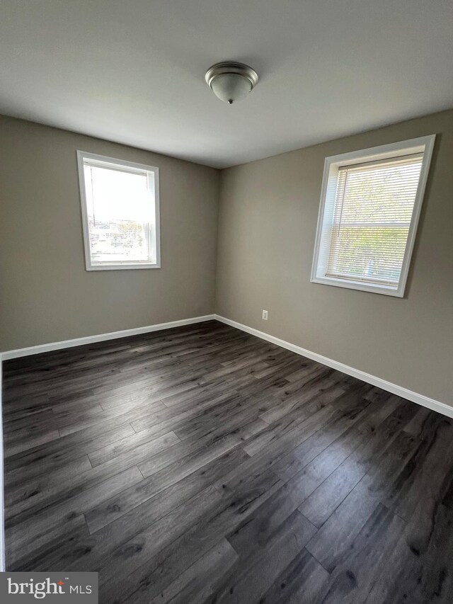1948 Victory Dr, Baltimore, MD 21227 - empty room featuring a healthy amount of sunlight, baseboards, and dark wood-style flooring