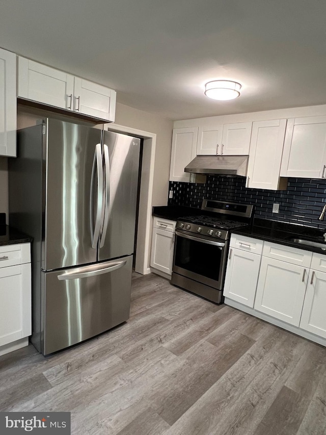 1948 Victory Dr, Baltimore, MD 21227 - kitchen featuring white cabinets, dark countertops, light wood-style flooring, stainless steel appliances, and under cabinet range hood