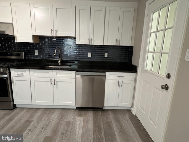 1948 Victory Dr, Baltimore, MD 21227 - kitchen with white cabinets, a sink, light wood-style floors, stainless steel appliances, and decorative backsplash