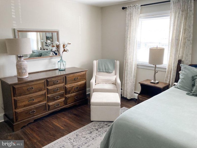 bedroom with dark wood-type flooring, baseboards, and baseboard heating