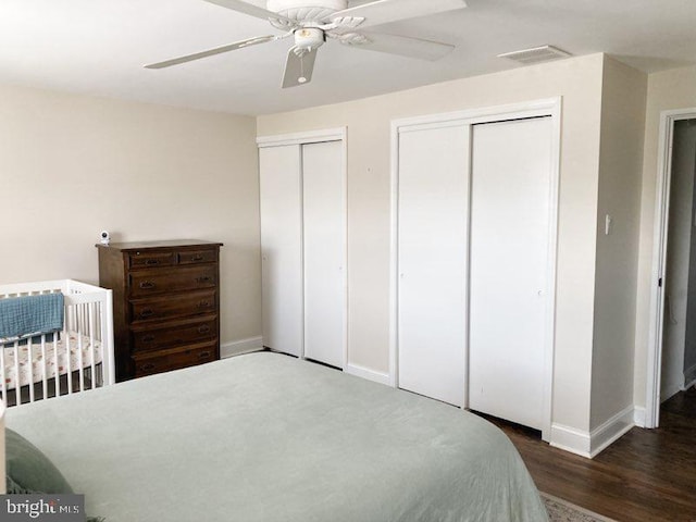 bedroom featuring ceiling fan, multiple closets, baseboards, wood finished floors, and visible vents