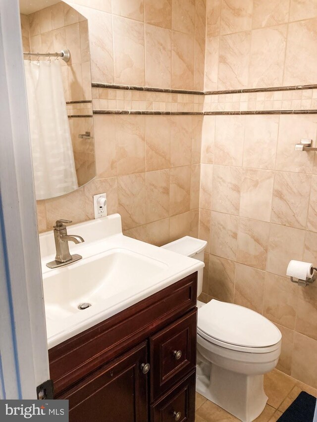 bathroom featuring toilet, tile walls, tile patterned flooring, and vanity