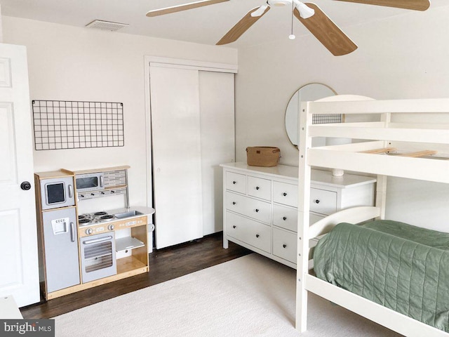 bedroom featuring a closet, dark wood finished floors, ceiling fan, and visible vents