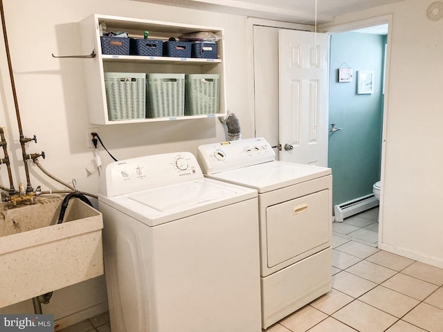 washroom with laundry area, washing machine and clothes dryer, light tile patterned floors, a sink, and a baseboard heating unit