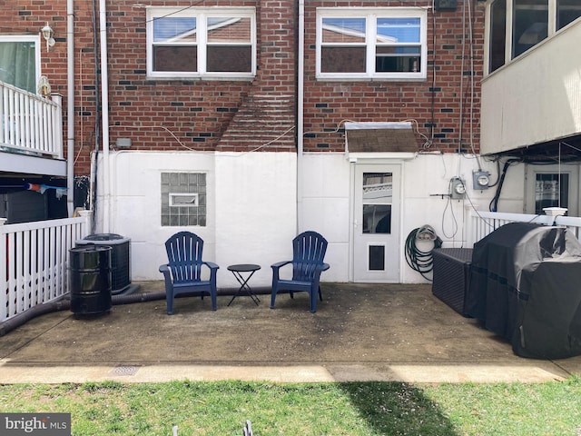rear view of house featuring brick siding, central AC unit, and a patio area