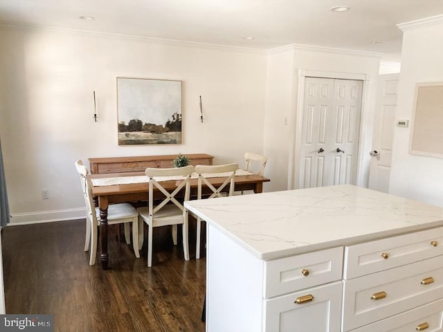 kitchen featuring a kitchen island, light stone counters, baseboards, ornamental molding, and dark wood-type flooring