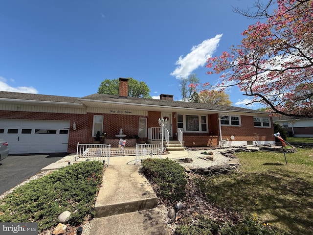 single story home featuring a chimney, a garage, aphalt driveway, and brick siding