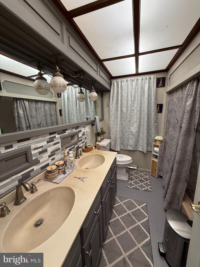 bathroom featuring double vanity, toilet, and a sink
