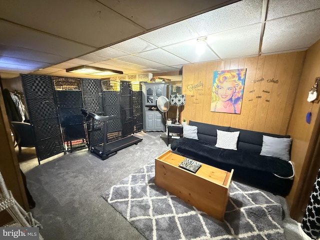 living room with wood walls, carpet, and a paneled ceiling