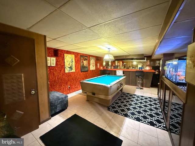 game room featuring light tile patterned floors, a paneled ceiling, pool table, and indoor bar