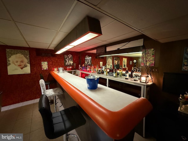 bar featuring tile patterned floors and a drop ceiling