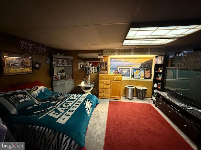 carpeted bedroom with wooden walls and a drop ceiling