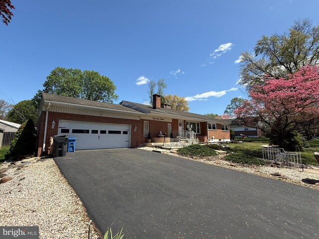 ranch-style home with a porch, driveway, a garage, and brick siding
