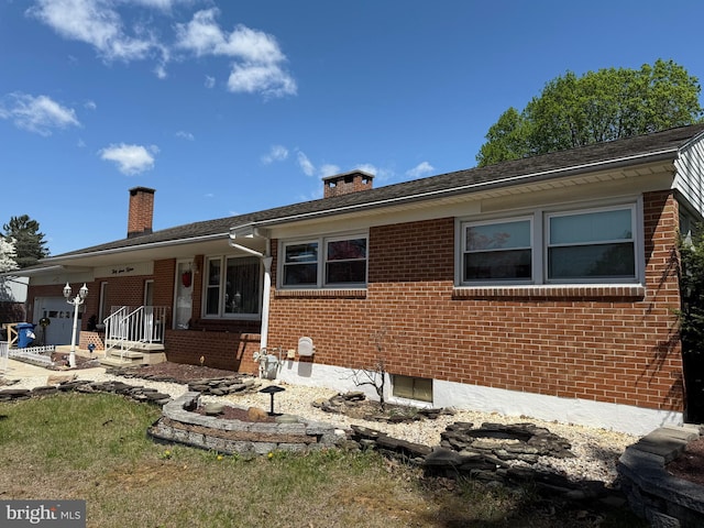 rear view of house with a chimney, an attached garage, and brick siding