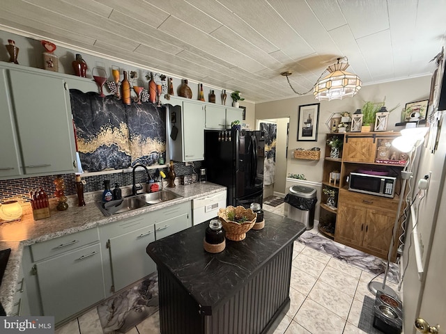 kitchen featuring stainless steel microwave, a sink, light tile patterned floors, backsplash, and freestanding refrigerator