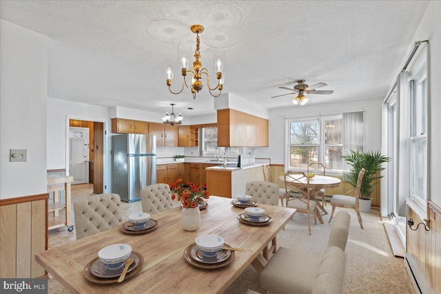 dining area with a baseboard radiator, a textured ceiling, a wainscoted wall, and ceiling fan with notable chandelier